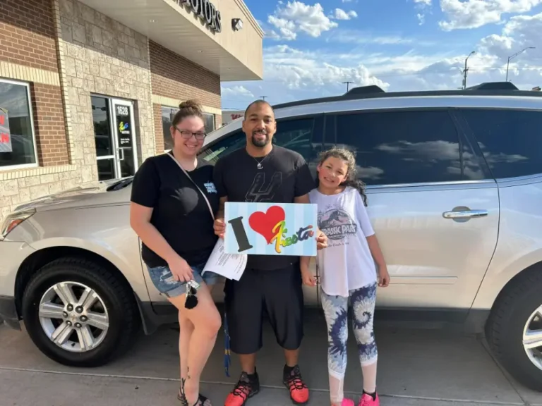 Happy family celebrating their car purchase at the dealership.